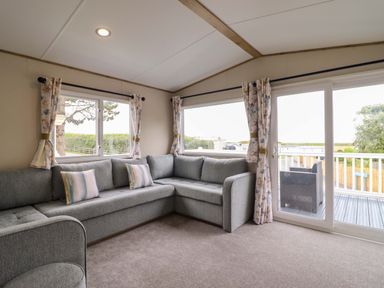 A snug with a gray sofa and windows at 8 Puffin Way Llwyngwril