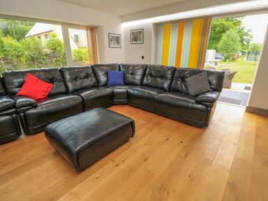 A living room with a black sofa and ottoman at Silver Copse Frilford Heath Near Abingdon