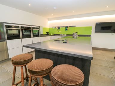 A kitchen with stovetop, stools, ovens and sink at Silver Copse Frilford Heath Near Abingdon