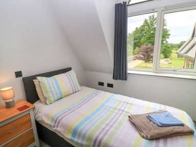 A bedroom with a bed and window at Silver Copse in Frilford Heath Near Abingdon