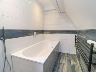 A bathroom with a bathtub and a towel radiator at Silver Copse Frilford Heath Near Abingdon