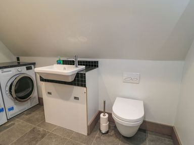 A bathroom with a washing machine, sink, and toilet at Silver Copse Frilford Heath Near Abingdon