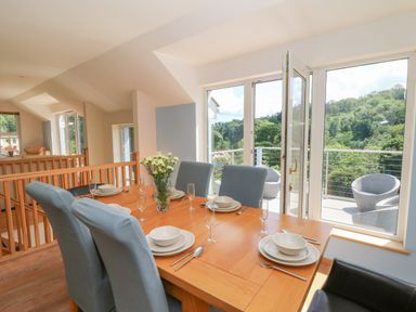A dining room with a table set and large windows at 1 Bryn Beudy in Stepaside