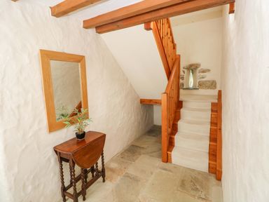 A hallway with a staircase and a mirror at Carreg Las in Haverfordwest