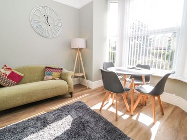 A living room with a clock on the wall at Flat 1A, Mona House in Conwy