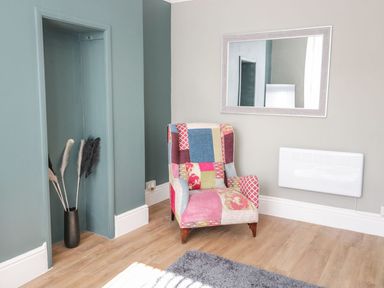 A living room with an armchair and a mirror at Flat 1A, Mona House in Conwy