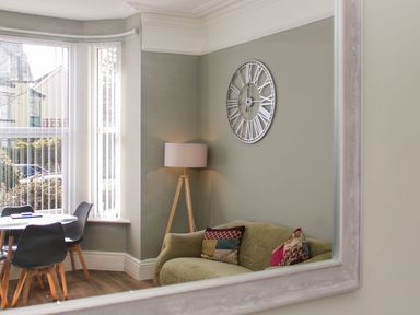 A living room with a sofa and floor lamp at Flat 1A, Mona House in Conwy