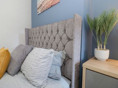 A bedroom with a bed, pillows, and a plant at Flat 1A, Mona House in Conwy