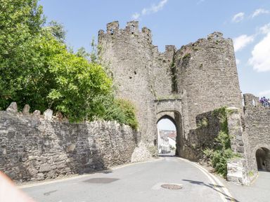 A stone castle with an archway and trees at Flat 1A, Mona House in Conwy