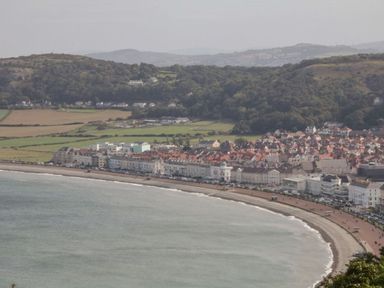 A view of a coastline with buildings along the shore at Flat 1A, Mona House in Conwy