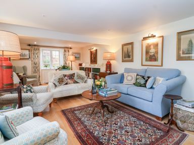 A living room with a sofa and armchair at Magdalen Cottage in Hook Norton