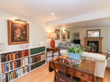 A living room with bookshelves and a sofa at Magdalen Cottage in Hook Norton