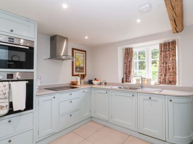 A kitchen with cabinets and appliances at Magdalen Cottage in Hook Norton