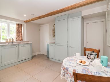 A kitchen with a table and chairs at Magdalen Cottage in Hook Norton