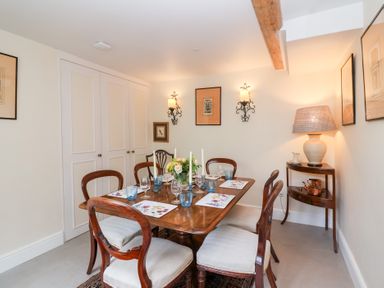 A dining room with a table set for a meal at Magdalen Cottage in Hook Norton