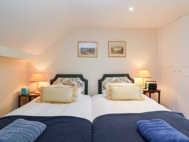A bedroom with two single beds and lamps at Magdalen Cottage in Hook Norton