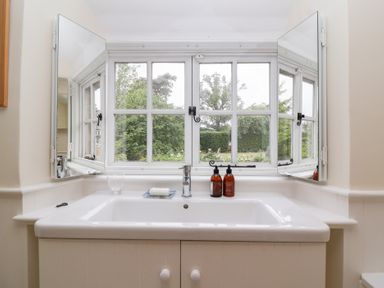A bathtub with a window in the bathroom at Magdalen Cottage in Hook Norton