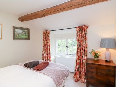 A bedroom with a bed and dresser at Magdalen Cottage Hook Norton