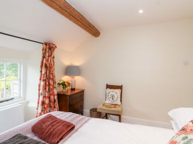 A bedroom with a bed and a window at Magdalen Cottage in Hook Norton