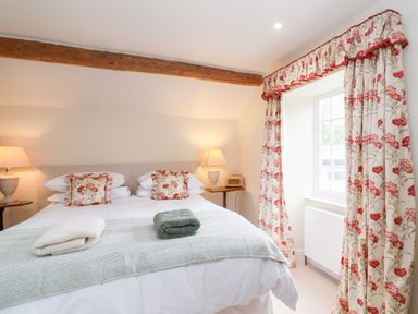A bedroom with a bed and bedside table at Magdalen Cottage in Hook Norton