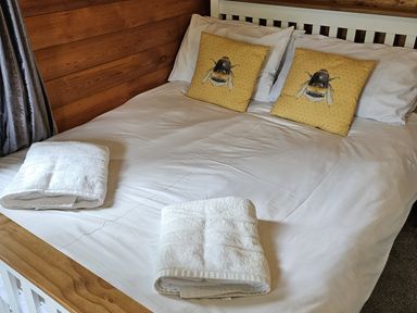 A bedroom with a double bed and bee patterned pillows at Swn Yr Afon - No 333 near Trawsfynydd