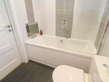 A bathroom with a bathtub and toilet at Lodge 83, Gwel an Mor in Portreath