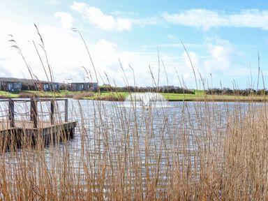 A view of water with a dock and buildings at Lodge 83, Gwel an Mor in Portreath
