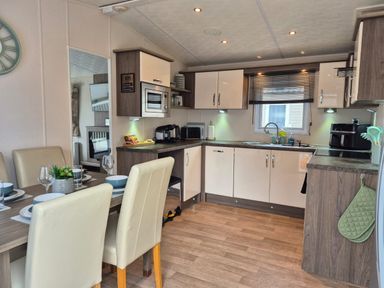 A kitchen with dining table and appliances at Fernwood Lodge in Fritton near Belton Norfolk