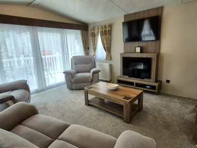 A living room with a sofa and armchair at Fernwood Lodge in Fritton near Belton, Norfolk