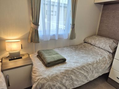 A bedroom with a bed and bedside table at Fernwood Lodge in Fritton near Belton, Norfolk