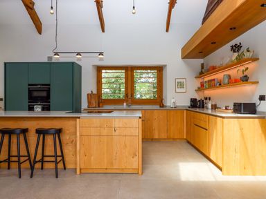A kitchen with an island and wooden cabinets at Lower Walreddon Barn in Tavistock