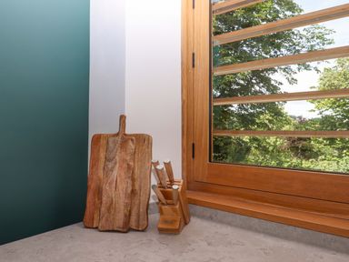 A kitchen area with a cutting board and knife block near a window at Lower Walreddon Barn in Tavistock