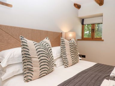 A bedroom with pillows and a window at Lower Walreddon Barn Tavistock