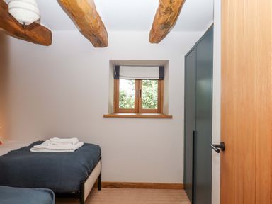 A bedroom with two beds and a window at Lower Walreddon Barn Tavistock
