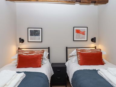 A bedroom with two beds and artwork on the wall at Lower Walreddon Barn in Tavistock