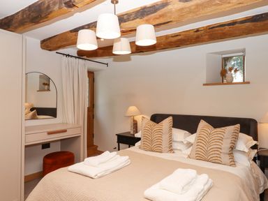 A bedroom with a bed and a dressing table at Lower Walreddon Barn in Tavistock