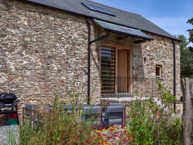 An outdoor area with stone wall and seating at Lower Walreddon Barn Tavistock