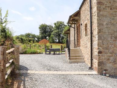 A stone building with stairs and outdoor furniture at Lower Walreddon Barn Tavistock