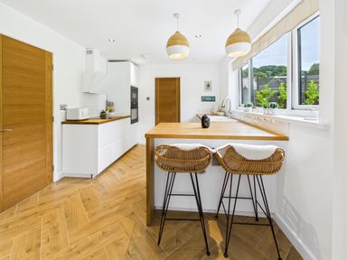 A kitchen with a counter and bar stools at 59a Gwscwm Road