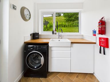 A laundry room with a washing machine and a sink at 59a Gwscwm Road