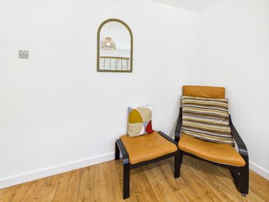 A living room with two chairs and a mirror at 59a Gwscwm Road
