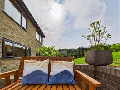 A garden with a wooden bench and cushions at 59a Gwscwm Road 