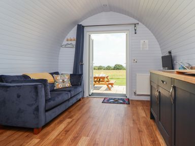 A living room with a sofa and door leading to an outdoor area at Honeypot Hideaways - Clover