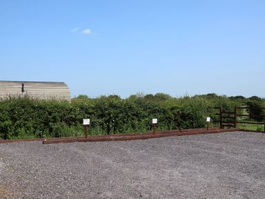 A parking area with gravel surface and signage at Honeypot Hideaways - Clover