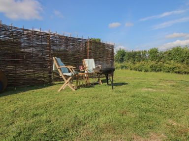 A garden with chairs and a table near a brazier at Squirrel's Drey in Chapel Lawn near Clun