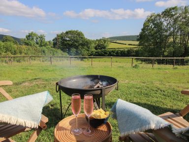 A fire pit with drinks and snacks in a garden at Squirrel's Drey in Chapel Lawn near Clun