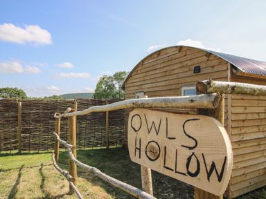 A wooden sign in front of a cabin at Owl's Hollow in Chapel Lawn near Clun