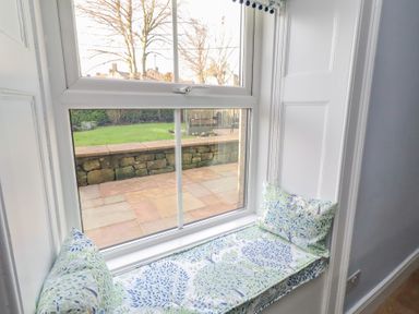 A window seat with cushions overlooking a garden at Linn Cottage in Hexham