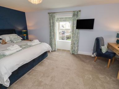 A bedroom with a bed and desk at Linn Cottage in Hexham