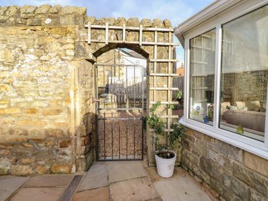 A garden with a stone wall and gate at Linn Cottage in Hexham